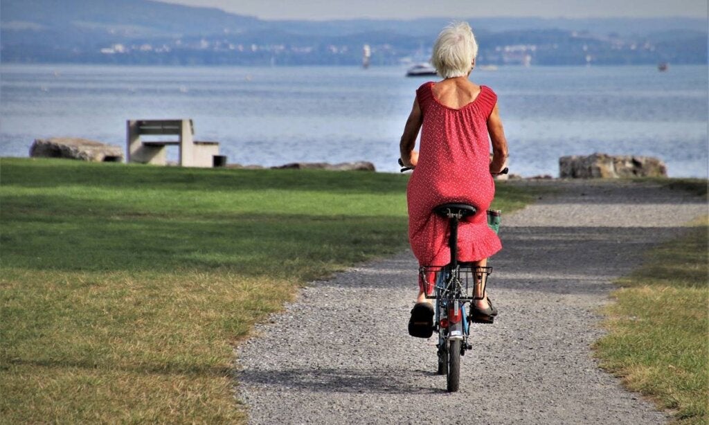 Yaşlılığa çiçek açan insanları temsil eden bisikletli kıdemli kadın