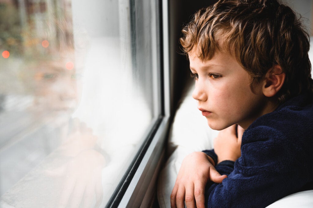 Bir kişiyi etiketlemenin zararlı etkisini simgeleyen pencereden dışarı bakan üzgün çocuk