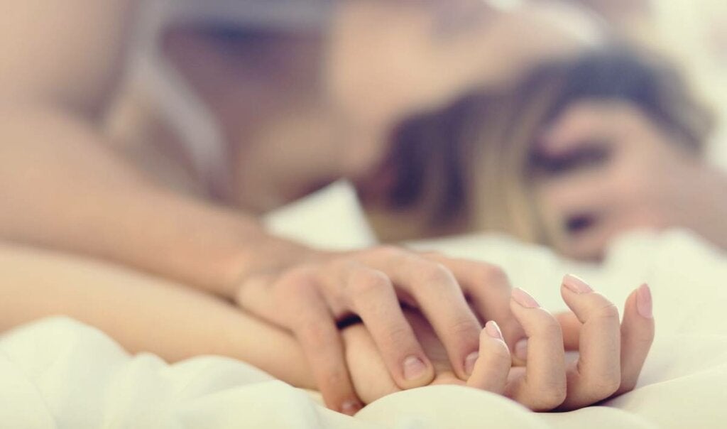 Yatakta bir çiftin kenetlenmiş elleri