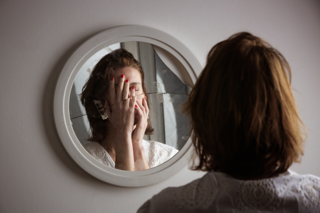 Aynanın önünde yüzünü kaplayan kadın