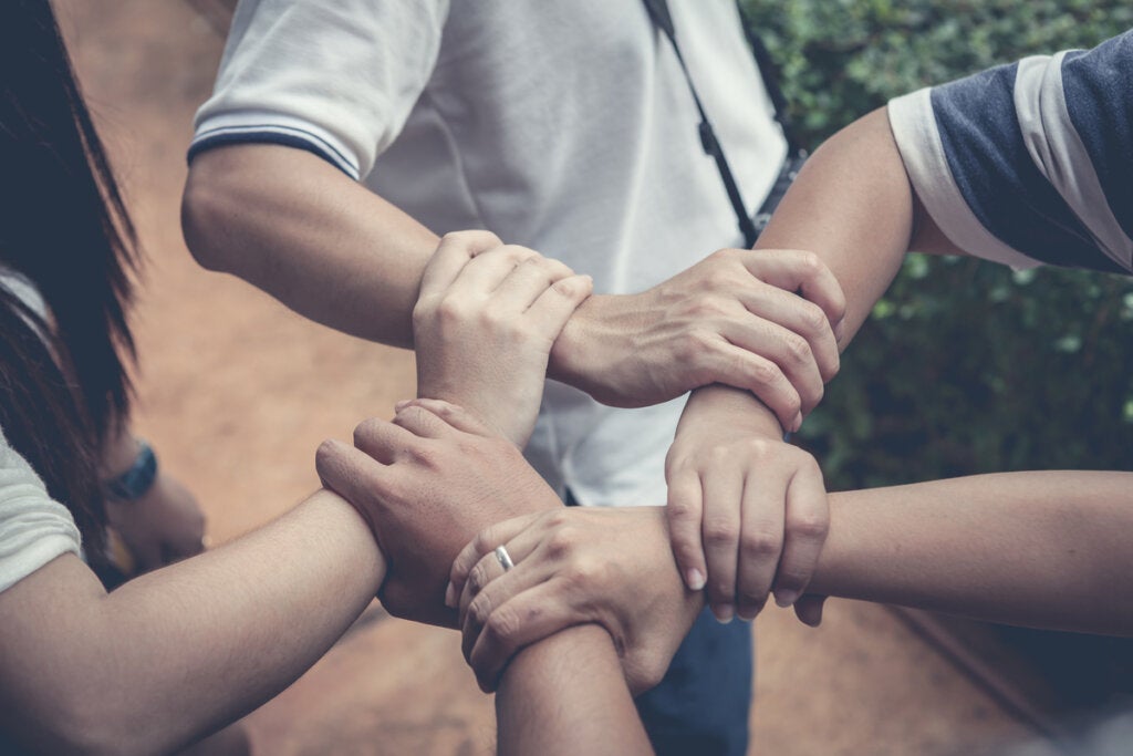 Birbirlerine yardım etmek için birbirlerinin kollarını tutan bir grup insan