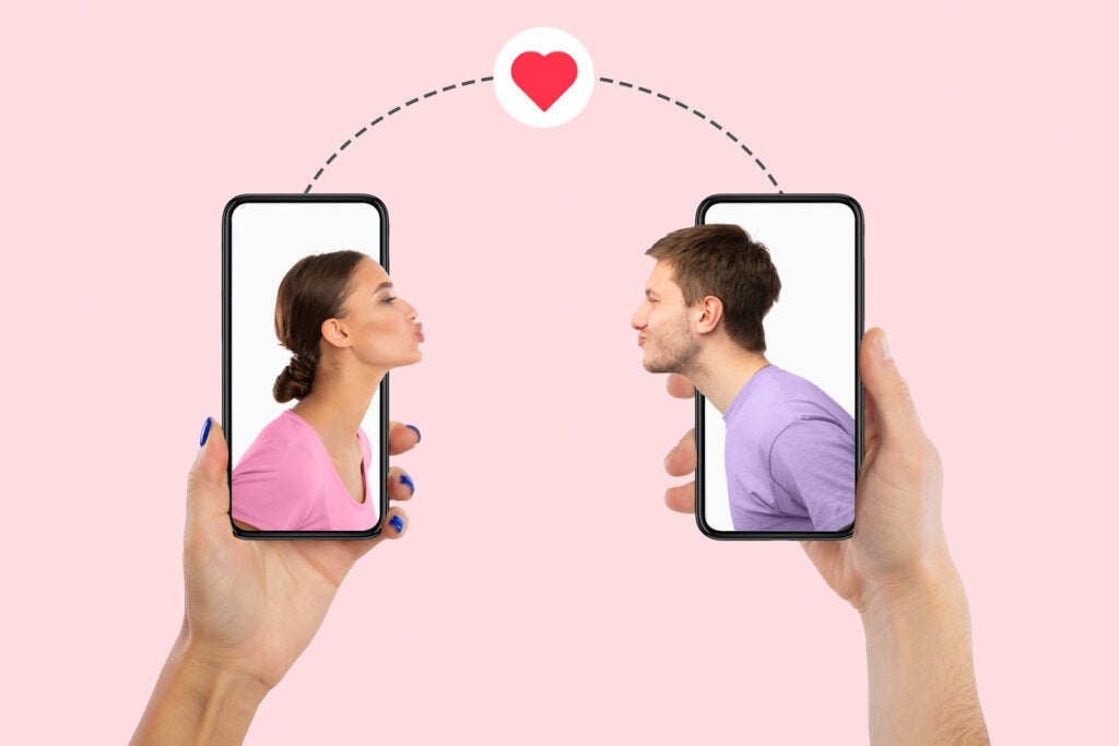 Cep telefonu kullanan kadın ve erkek, flört uygulamalarında birbirlerine öpücük gönderiyor.