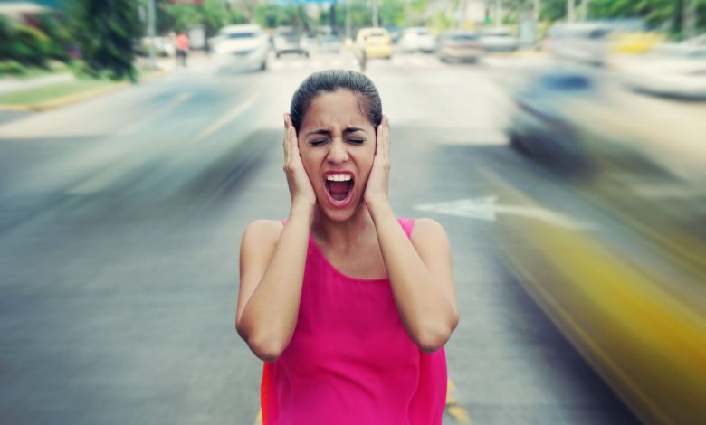 Mujer tapándose los oídos por la contaminación acústica