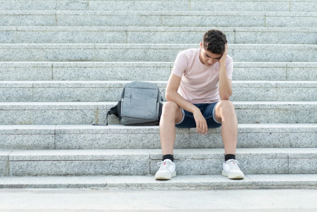 Merdivenlerde oturan üzgün genç