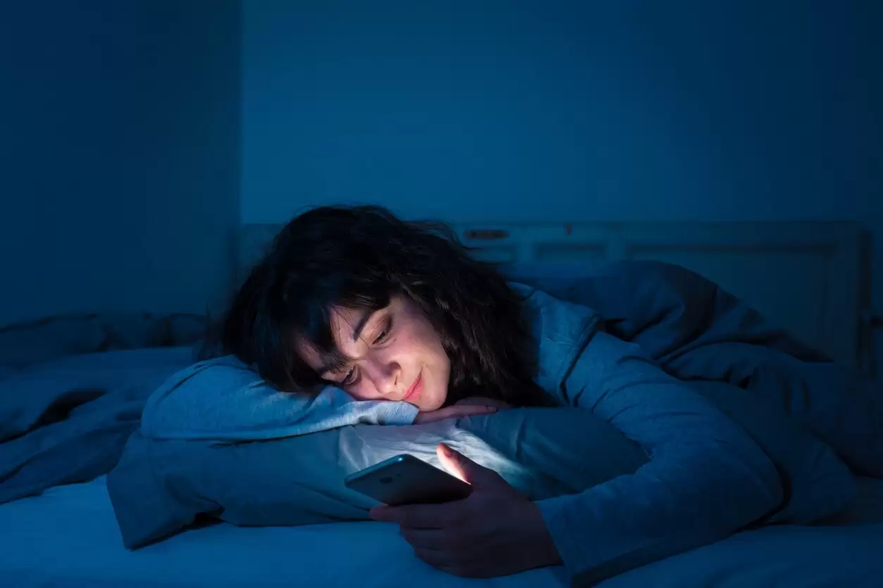 Mujer pensando en apagar el móvil antes de ir a dormir