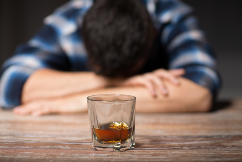 Alkol içmenin ruh halinizi iyileştirmediğini simgeleyen bir bardak alkollü adam