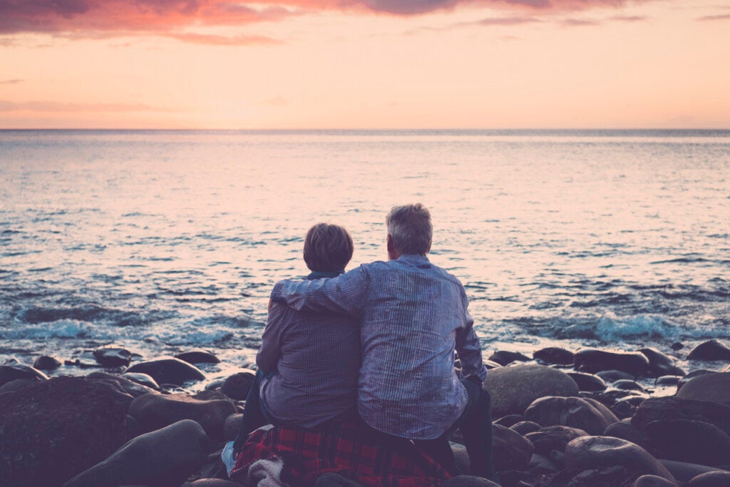 Yaşlı çift gün batımında denizde oturup birbirlerine sarılıyorlar.  ruh eşleri efsanesini düşünmek