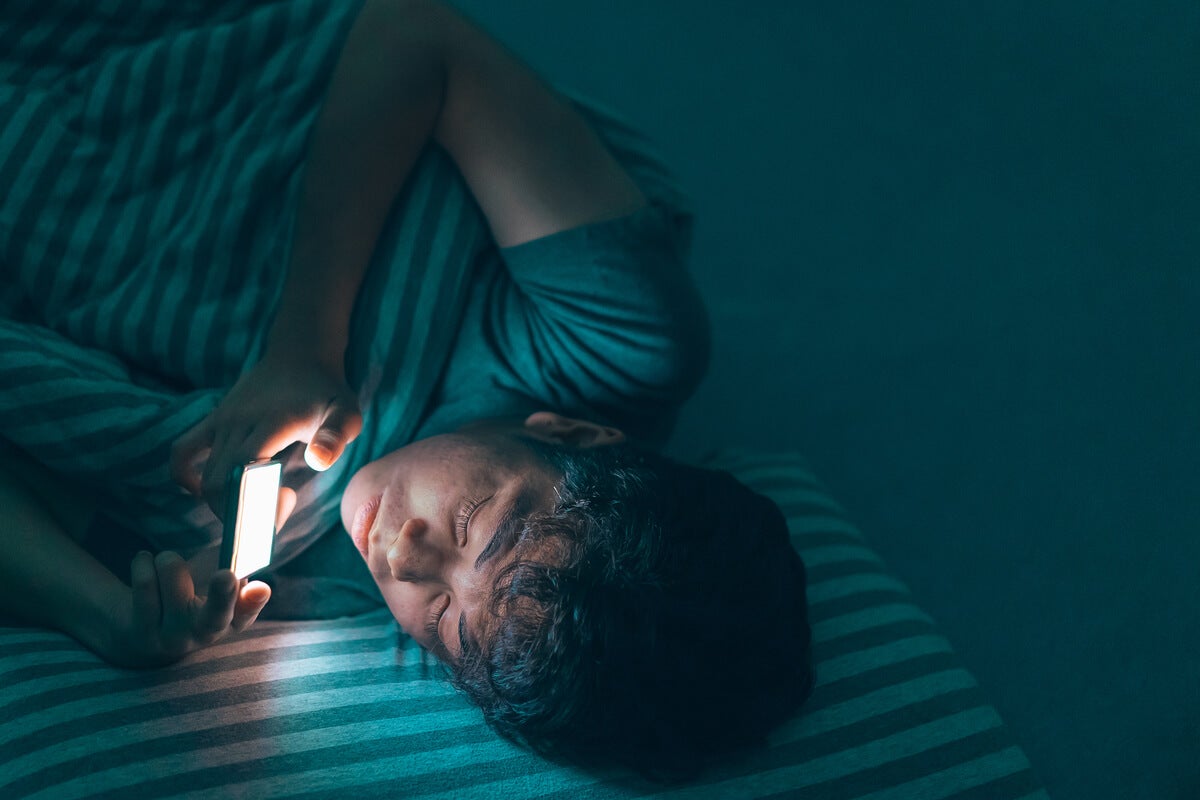 Gece yatakta cep telefonu kullanan genç